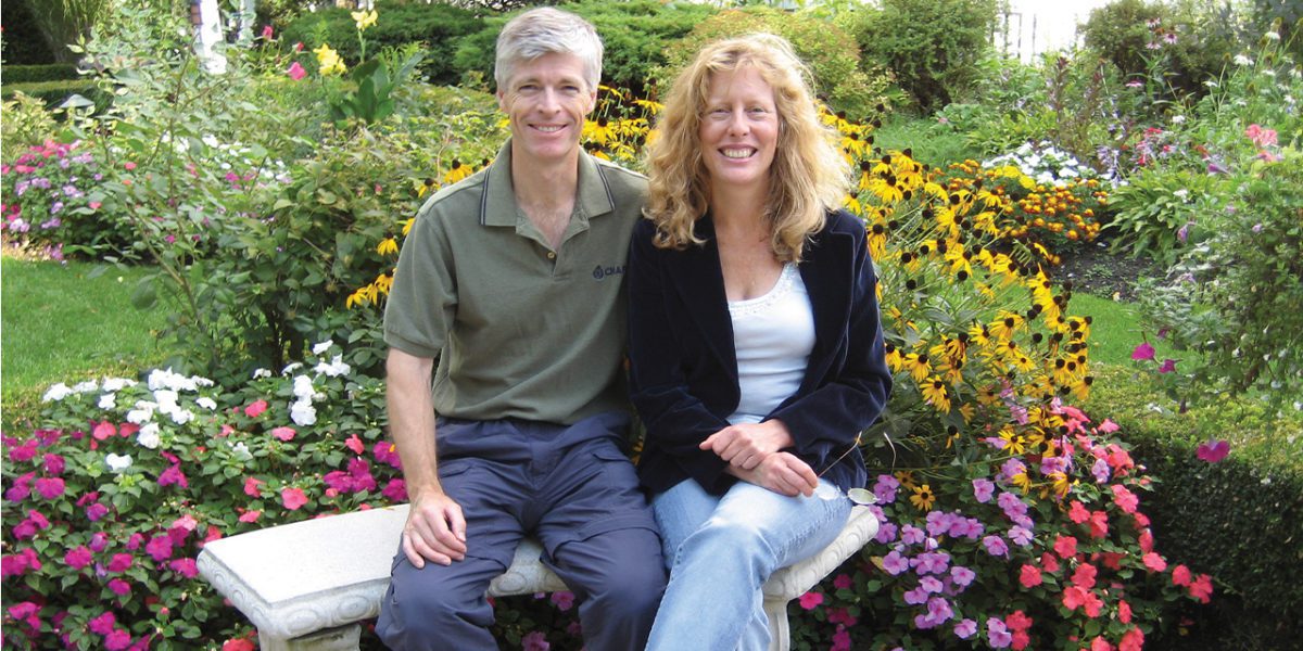 Couple d'âge moyen assis ensemble dans leur jardin en souriant