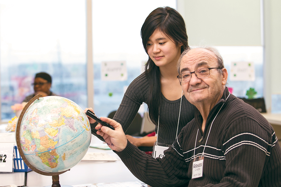 Un aîné atteint d’aphasie pointe à un globe avec une jeune femme